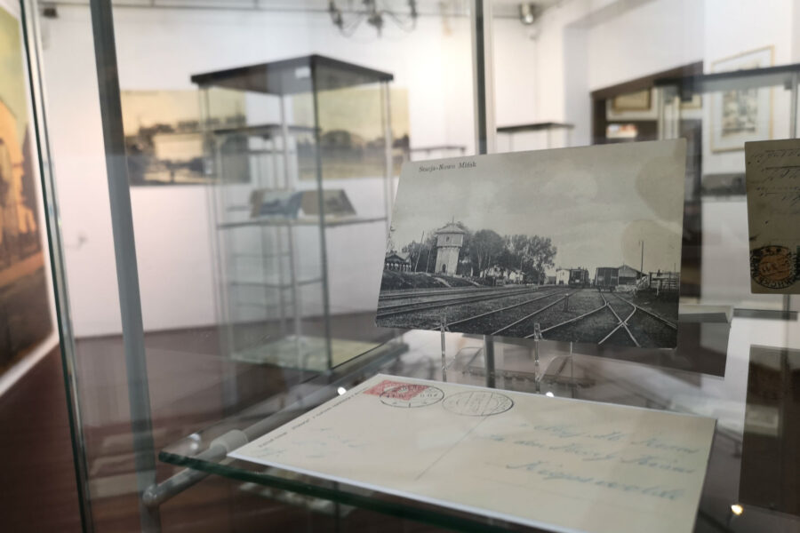 Wnętrze gabloty. Na pierwszym planie pocztówka z historycznym widokiem stacji kolejowej w Mińsku Mazowieckim. W tle reszta ekspozycji.