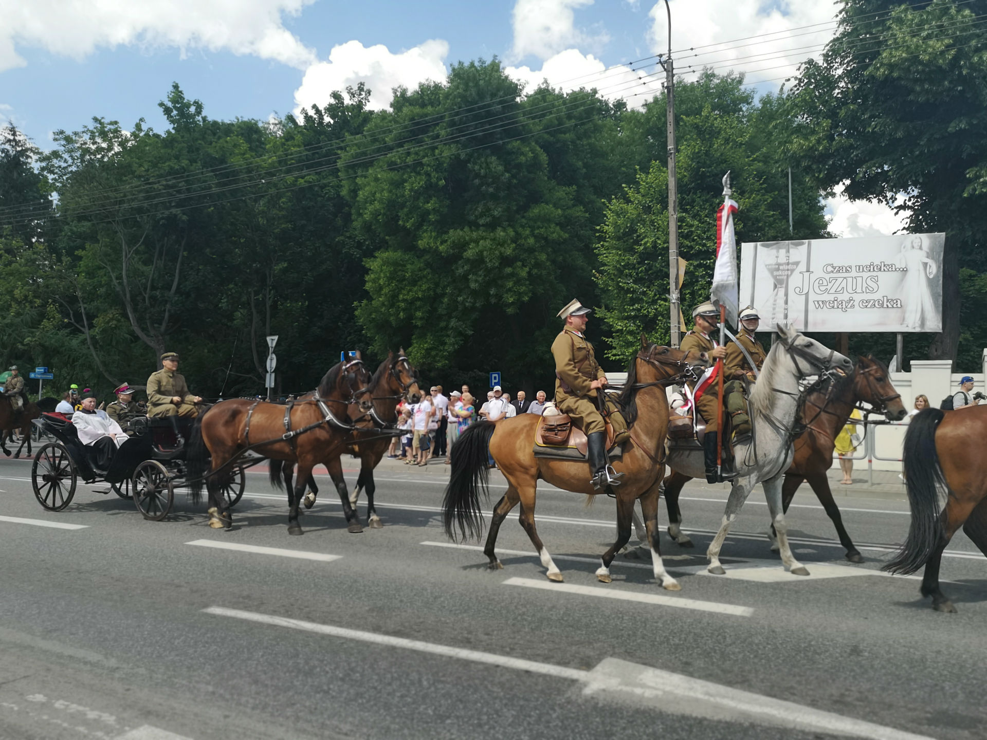 Parada z okazji obchodów 100-lecia przybycia 7 Pułku Ułanów Lubelskich do Mińska Mazowieckiego. Ulicą miasta jadą konno żołnierze ubrani w historyczne, zielone mundury oraz rogatywki z białym paskiem. Za nimi, w dorożce prowadzonej przez dwa konie siedzi osoba duchowna w towarzystwie dwóch żołnierzy.